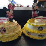 Two mickey mouse birthday cakes on a table.