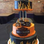 A harley davidson cake with a motorcycle on top.