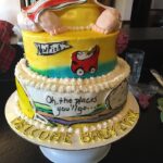 A cake with a baby sitting on top of it.