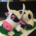 A cow cake with daisies on top.