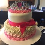 A pink and white cake with a tiara on top.