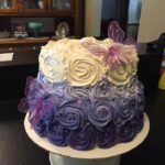 A white and purple cake with butterflies on top.