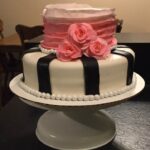 A black and white cake with pink roses on top.