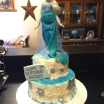 A frozen birthday cake with a mermaid on top.