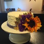 A white cake with purple flowers on top.