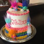 A cake decorated with trolls and rainbows.