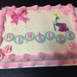 A pink and white cake with the name rinnelle on it.