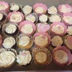 A box of cupcakes with pink icing and hearts.