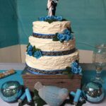 A three tier wedding cake with blue flowers.