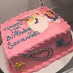 A pink cake with a unicorn on it.