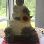 A wedding cake with sunflowers on top.