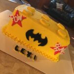 A yellow batman birthday cake is on a table.