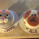 Two cakes with a cat and a dog on them.