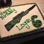 A birthday cake with a rifle on it.