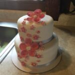 A white cake with pink flowers on top.