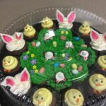 A tray of cupcakes decorated with easter bunnies and chicks.