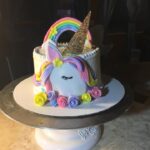 A cake with a unicorn on top of it.