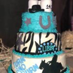 A cake decorated with zebra stripes and a cowboy hat.