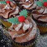 Chocolate christmas cupcakes with holly decorations.