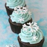 Three cupcakes decorated with blue frosting and snowflakes.