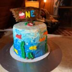 A cake with a fish on it and a sign that says one.