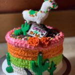 A cake decorated with a llama and cactus.