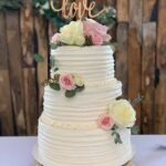 A white wedding cake with flowers on top.