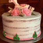 A cake decorated with a llama and flowers.