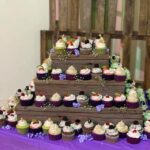 A tall tower of cupcakes on a purple table.