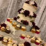 A cake stand with cupcakes and flowers on it.