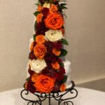 A wedding cake decorated with orange and white flowers.