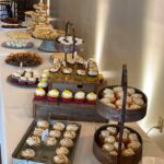 A long table with a variety of desserts on it.