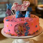 A pink cake with a picture of person on it.