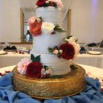 A wedding cake with blue and red flowers on top.