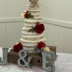 A wedding cake on top of a wooden board.