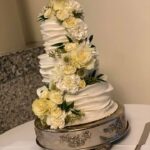 A white and yellow wedding cake on a table.