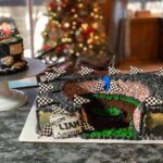 A cake decorated like a race track with a checkered flag.