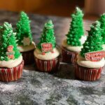 Cupcakes decorated with christmas trees on a counter.