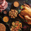 A table full of turkey, vegetables, and desserts.