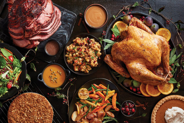 A table full of turkey, vegetables, and desserts.